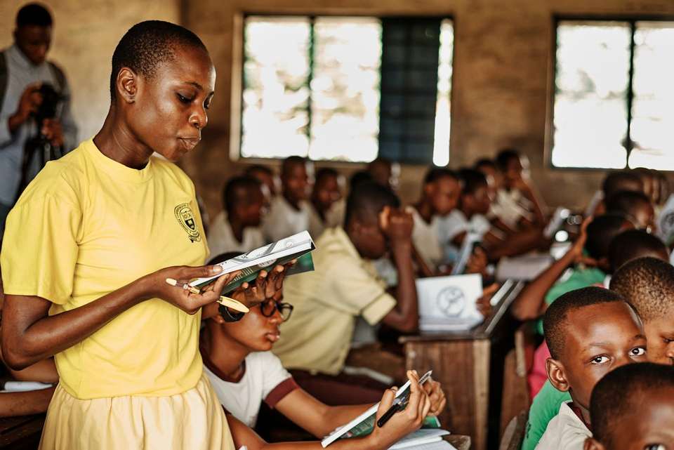 A teacher reading with learners in a Sierra Leonean classroom